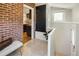 Hallway view with exposed brick showing access to the kitchen, featuring hardwood floors and natural light at 3743 N Yates St, Denver, CO 80212