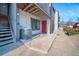 View of the building's exterior featuring a red front door, A/C, and access to stairs at 6380 Oak St # 107, Arvada, CO 80004