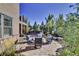 A circular stone patio with comfortable seating overlooks a lush, beautifully landscaped yard at 10553 Fairhurst Way, Highlands Ranch, CO 80126