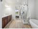 Bright bathroom features a glass shower, soaking tub, double vanity, and wood-look tile flooring at 10553 Fairhurst Way, Highlands Ranch, CO 80126