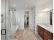 Bright bathroom featuring a glass shower, soaking tub, double vanity, and wood-look tile flooring at 10553 Fairhurst Way, Highlands Ranch, CO 80126