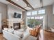 Cozy living room featuring a stone fireplace, hardwood floors, exposed beams, and access to the patio at 10553 Fairhurst Way, Highlands Ranch, CO 80126