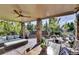Covered patio with ceiling fan, dining area, and comfortable seating surrounded by lush landscaping at 10553 Fairhurst Way, Highlands Ranch, CO 80126
