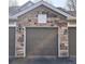 A garage with a brown door is accented by a stone facade at 12711 Colorado Blvd # 912, Thornton, CO 80241