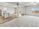 A spacious living area with gray carpeted floors, a kitchen with an island, and ample natural light at 2175 Alyssa St, Fort Lupton, CO 80621