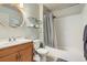 Bright bathroom with a wood vanity, a round mirror, floating shelves and a shower-tub combo at 15976 E Radcliff Pl # A, Aurora, CO 80015