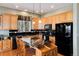 The well-lit kitchen features wooden cabinets, black appliances, granite counters, and an island with barstool seating at 11302 Mesa Verde Pl, Parker, CO 80138