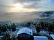Panoramic aerial view of a snow-dusted house with solar panels amidst a misty mountain landscape at 8 Sioux Trl, Evergreen, CO 80439