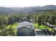 Aerial view of the home with solar panels atop the roof with a lush forest of trees in the background at 8 Sioux Trl, Evergreen, CO 80439