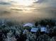Aerial view of the sun rising over the mountains and the property covered in a blanket of snow and frost at 8 Sioux Trl, Evergreen, CO 80439