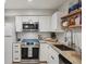 A renovated kitchen featuring stainless steel appliances, light granite counters and wooden shelving at 5300 E Cherry Creek South Drive # 918, Denver, CO 80246