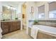 Bathroom featuring a soaking tub, tiled shower, and a wooden vanity with ample counter space at 3366 Willow St, Denver, CO 80238