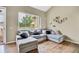 Bright living room featuring a plush sectional sofa, hardwood floors, and a large window showcasing outdoor greenery at 1099 S Walden Way # 205, Aurora, CO 80017