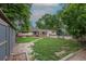 A brick ranch-style home features a brick and gravel path, a small shed, and a grass yard surrounded by mature trees at 5810 S Greenwood St, Littleton, CO 80120