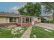 A tan brick home is surrounded by mature trees and features a brick and gravel path and a sunroom at 5810 S Greenwood St, Littleton, CO 80120