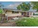 A tan brick home is surrounded by mature trees and features a brick and gravel path and an egress window at 5810 S Greenwood St, Littleton, CO 80120