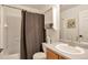 This bathroom features a single sink vanity, framed mirror and tub with shower and linen storage at 1030 E 78Th Pl, Denver, CO 80229