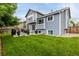 Landscaped backyard with lush green lawn, a modern patio area with outdoor dining, and mature trees at 6888 Howell St, Arvada, CO 80004
