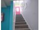 Staircase with gray carpeting and colorful walls and accents, leading to an upper level with a pink door at 7799 Pecos St, Denver, CO 80221