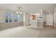 Open living room with neutral carpet, windows, and access to the kitchen at 5779 Ceylon St, Denver, CO 80249