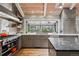 Bright kitchen with a gas range, stone countertops, floating shelves, stainless steel appliances, and oversized window at 5145 S Logan Dr, Littleton, CO 80121