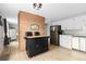 Bright kitchen featuring white cabinetry, stainless steel appliances, brick wall accents, and functional island at 11827 Brook Rd, Golden, CO 80403