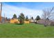 Spacious backyard with lush green grass, mature trees, and a wooden fence at 574 El Paso Rd, Palmer Lake, CO 80133