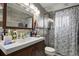 Modern bathroom features a vanity with a white sink, wood cabinet, decorative shower curtain and light fixtures above the mirror at 1390 S Ammons St, Lakewood, CO 80232