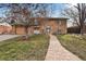 Charming stone facade home with a paved walkway leading to the front door and manicured front yard at 1390 S Ammons St, Lakewood, CO 80232