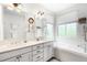 Bright bathroom featuring a double vanity, soaking tub, and window with natural light at 3320 Yukon Ct, Wheat Ridge, CO 80033