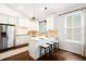 Bright kitchen features stainless steel appliances, white cabinets, pendant lighting, and an eat-in bar at 3320 Yukon Ct, Wheat Ridge, CO 80033