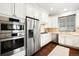 Modern kitchen with stainless steel appliances, white cabinets, tile backsplash and a patterned rug at 3320 Yukon Ct, Wheat Ridge, CO 80033