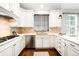 Modern white kitchen features stainless steel appliances and stone tile backsplash at 3320 Yukon Ct, Wheat Ridge, CO 80033