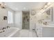 Bright bathroom featuring a soaking tub, glass shower, and decorative vanity with brass fixtures at 13818 Krameria St, Thornton, CO 80602
