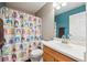 Well-lit bathroom with a printed shower curtain, vanity, sink, and mirror at 13818 Krameria St, Thornton, CO 80602