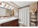 Bright bathroom featuring a wood vanity, white countertops, decorative shelves, and a shower with a curtain at 13818 Krameria St, Thornton, CO 80602
