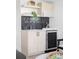 Close up of a bar area featuring light wooden cabinets, a wine fridge, and black backsplash at 2090 Eliot St, Denver, CO 80211