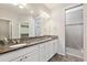 Bathroom with dual sink vanity, granite counters, white cabinets, and tiled shower at 19802 E 54Th Ave, Denver, CO 80249