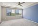 Bright bedroom with a ceiling fan, two windows, and an accent wall painted in calming blue at 19802 E 54Th Ave, Denver, CO 80249