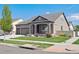 Charming home featuring manicured lawn, inviting front porch, and a three-car garage, set under a clear blue sky at 19802 E 54Th Ave, Denver, CO 80249