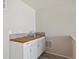 This kitchenette features white cabinets, a wood countertop, backsplash, and a stainless steel sink and faucet at 19802 E 54Th Ave, Denver, CO 80249