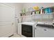 Functional laundry room featuring modern washer and dryer, ample shelving, and a convenient storage area at 19802 E 54Th Ave, Denver, CO 80249