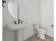 Elegant half bath features pedestal sink, modern fixtures, and a round mirror at 25303 E Warren Pl, Aurora, CO 80018