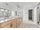 Modern bathroom featuring a double vanity, frameless glass shower, and neutral tile at 25303 E Warren Pl, Aurora, CO 80018
