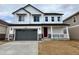 Charming two-story home featuring a gray garage door, a red front door, and a cozy front porch at 25303 E Warren Pl, Aurora, CO 80018
