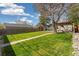 Spacious backyard with a lush lawn, wooden fence, mature trees, and a patio area, perfect for outdoor activities at 4916 Knox Ct, Denver, CO 80221
