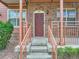 Charming brick home entrance featuring a red front door, concrete steps, and decorative railings at 5467 Zephyr Ct # 5467, Arvada, CO 80002