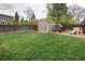 Green backyard featuring a wooden fence, storage shed, playhouse, and a manicured lawn at 6141 S Estes St, Littleton, CO 80123