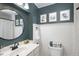 Stylish bathroom with wainscoting, white vanity, round mirror, and shower with a patterned curtain at 6141 S Estes St, Littleton, CO 80123