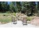 Relaxing backyard with chairs facing a tranquil stream and surrounded by mature trees at 8171 S Homesteader Dr, Morrison, CO 80465